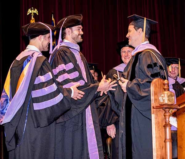 Class of 2018 president Dr. Joshua Lovick (at left) and vice president Dr. Chad Dickerson presented Dr. Luis Sensi with the Outstanding Faculty Award at graduation on May 4.
