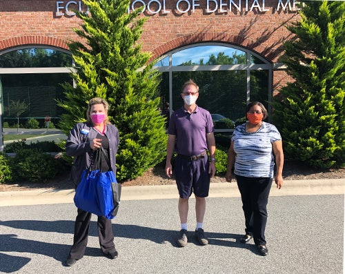 Julie Helms picking up masks from Duncan Jennings with NCDS for Dr Sara Frye. They are pictured with Gloria Oglesby, right, business manager of the Davidson County community service learning center.