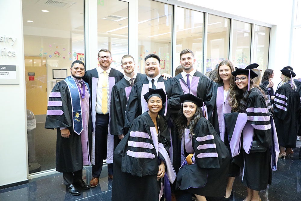 Group of students in hallway wearing graduation attire.