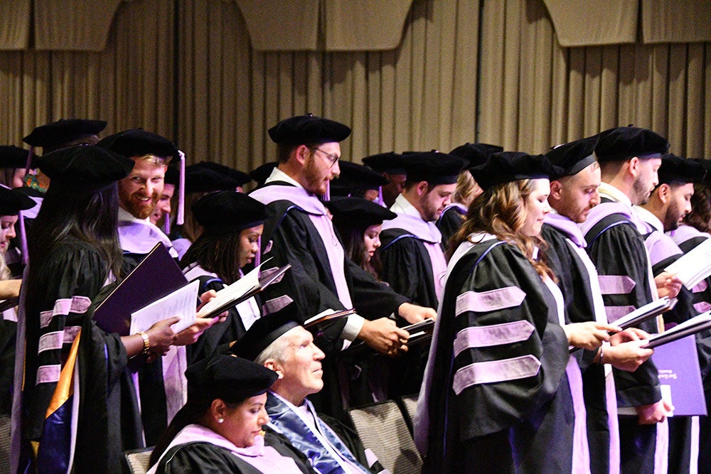 Graduates, standing reciting a pledge.