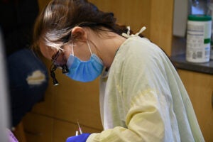 Dental student looking down, working on a patient