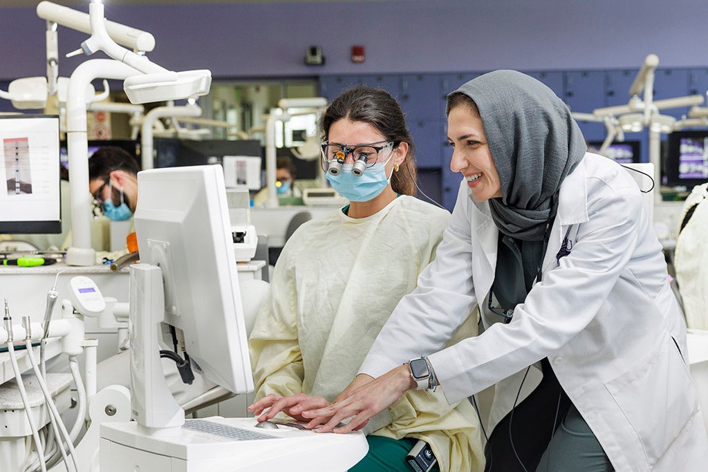 Two women working on a digital dental machine in a lab.