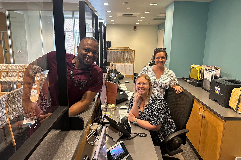 Three people standing at reception desk.