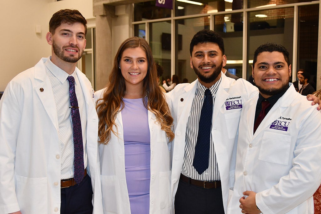 Students posing in lab coats.