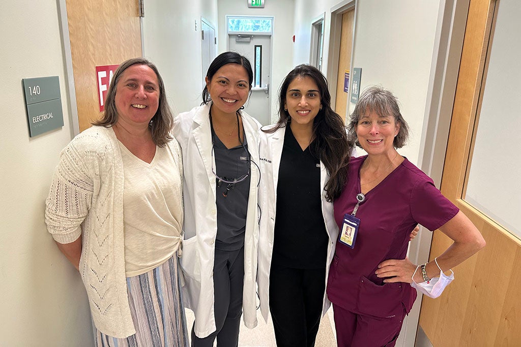 Four women posing in hallway.