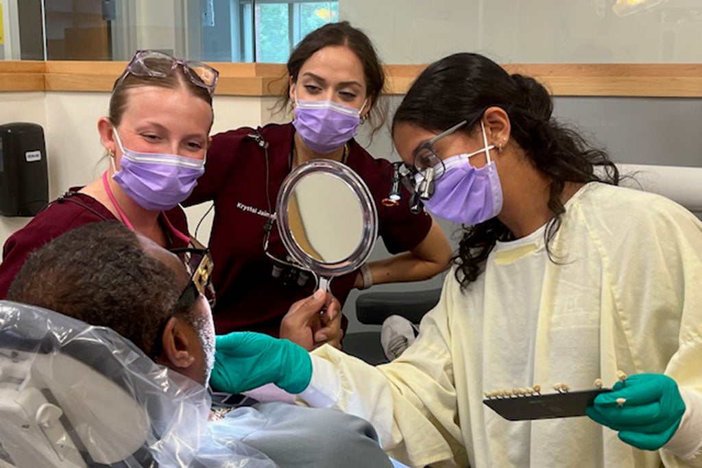 Four dentist treating a patient.