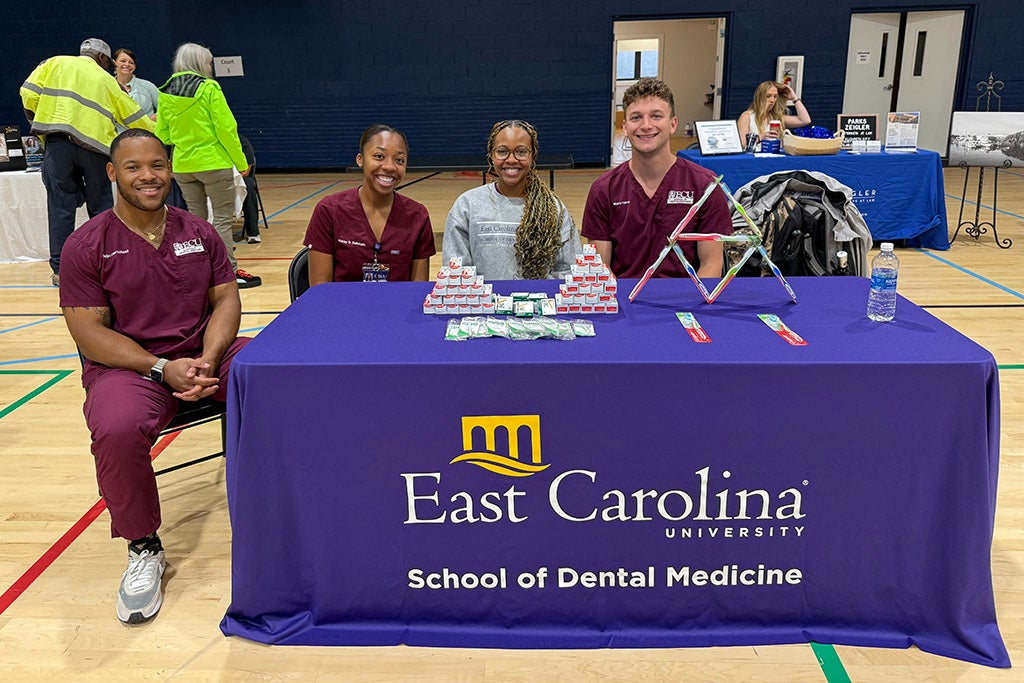 Dental students sitting at a table in a gym.