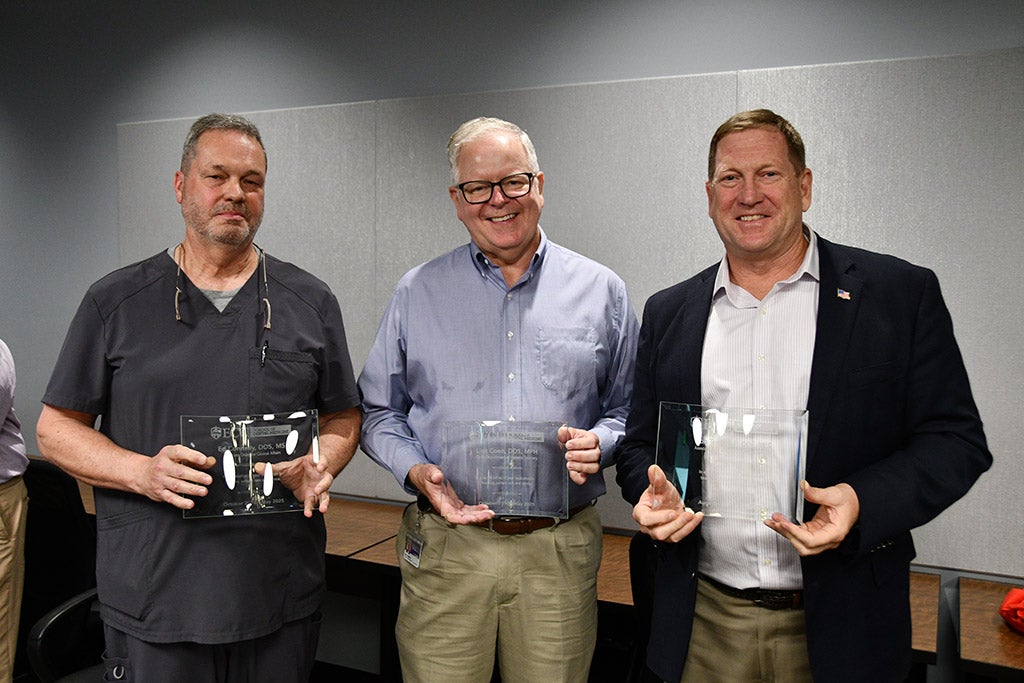 Three men posing with awards.