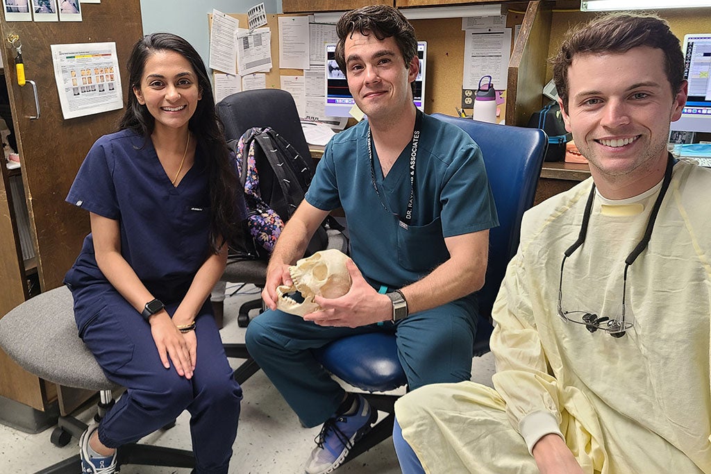 Three dental students sitting in chairs.