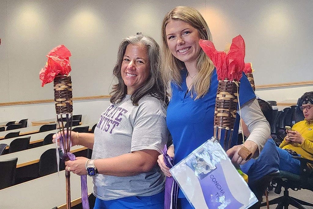 Two students holding tiki torches.
