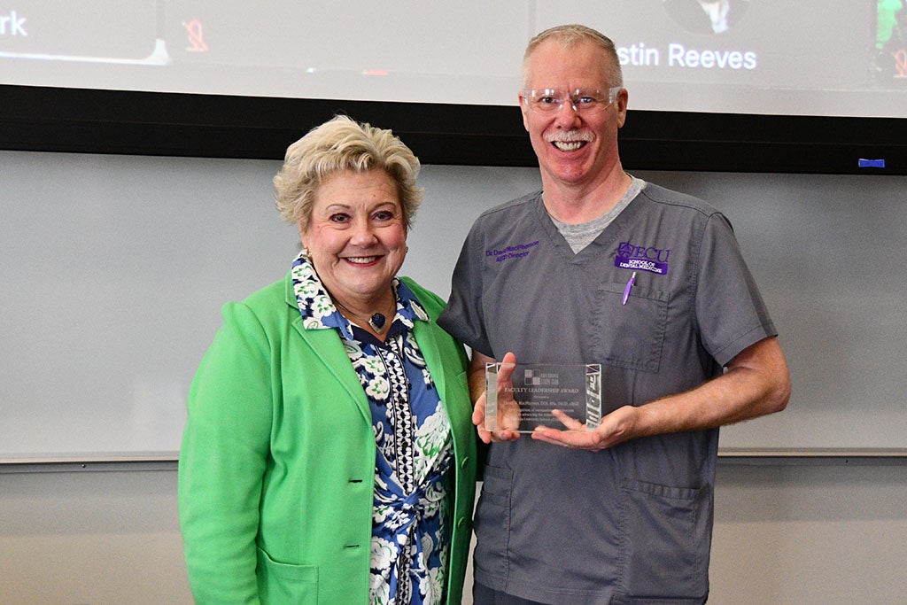Two people posing with an award.