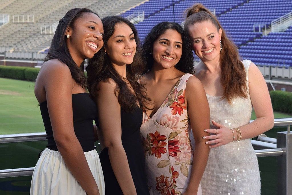 Four women at a football stadium.
