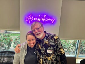 A photo of 2 people posing under a neon sign. 