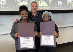 Three people posing with certificates.